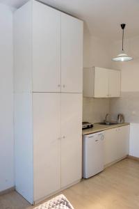 a white kitchen with white cabinets and a sink at Cleopatra Apartments in Laganas