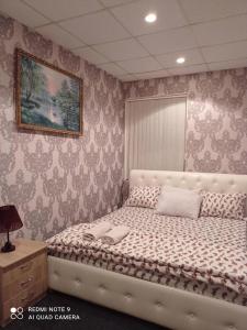 a bedroom with a white bed with a picture on the wall at DESYATINNAYA Hostel in Kyiv