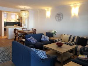 a living room with blue chairs and a table at Santos Beach Pavilion - Flat B in Mossel Bay