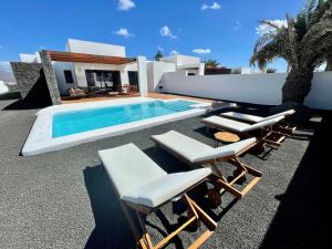 une villa avec une piscine et quelques chaises dans l'établissement Villalia Tahona, à Playa Blanca