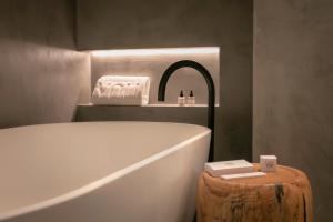 a bathroom with a bath tub and a wooden stump next to a table at Only YOU Hotel Málaga in Málaga