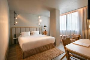 a bedroom with a bed and a table and a desk at Only YOU Hotel Málaga in Málaga