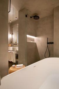 a bathroom with a tub and a shower with a mirror at Only YOU Hotel Málaga in Málaga