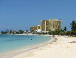a beach with people swimming in the water and buildings at Marchabell by the Sea E22 in Ocho Rios