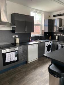 una cocina con armarios negros y electrodomésticos blancos en Cooperage House All Ensuite Property - Sleeps 18 en Sheffield