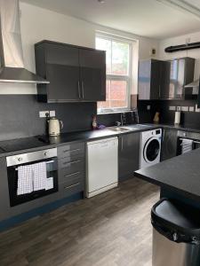 a kitchen with black cabinets and white appliances at 8 Bed 9 Bath Ensuite House with Hot Tub and Free Parking in Sheffield +36 photos