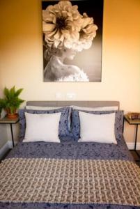 ein Schlafzimmer mit einem Bett mit einem Blumenbild an der Wand in der Unterkunft Hues Piece Paynes Farm in Broad Clyst