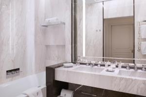 a white bathroom with a sink and a mirror at Hôtel de Paris Monte-Carlo in Monte Carlo
