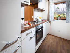 a small kitchen with white appliances and wooden floors at Pension Mooserlehen in Bischofswiesen +18 photos