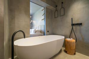 a white bath tub in a bathroom with a bedroom at Only YOU Hotel Málaga in Málaga