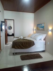 a bedroom with a large white bed and a bathroom at Flat Galemares in Maragogi