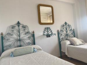 - une chambre avec 2 lits et un miroir mural dans l'établissement Tita Uchi en la Playa Grupo AC Gestion, à Cadix