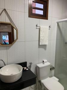 a bathroom with a white toilet and a sink at Flat Galemares in Maragogi
