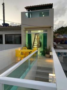 a balcony of a house with a table and yellow chairs at Flat Galemares in Maragogi