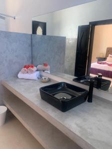 baño con lavabo negro y espejo en Riad le Jasmin en Taroudant