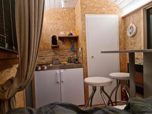 eine Küche mit einem Waschbecken und 2 Hockern in einem Zimmer in der Unterkunft La roulotte in Travers