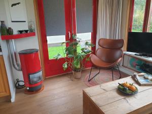 a living room with a red door and a chair at Repelsteeltje op Terschelling in Formerum