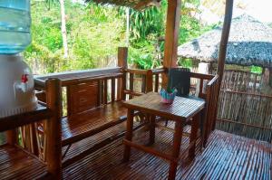 a wooden porch with a wooden table and a table at Titanic's Nipa Hut in Moalboal