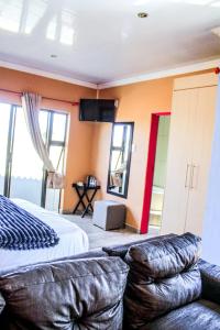 a bedroom with a bed and a couch and a television at Thavhani Guest House in Thohoyandou