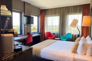 una camera d'albergo con letto, scrivania e sedie di XO Hotels Couture ad Amsterdam