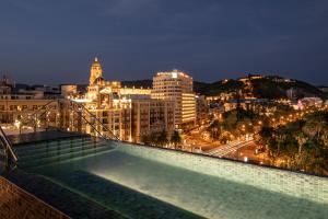 a view of a city at night with a swimming pool at Only YOU Hotel Málaga in Málaga