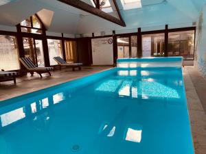 a swimming pool with blue water in a building at Logis Le Clos Deauville Saint Gatien in Saint Gatien des Bois