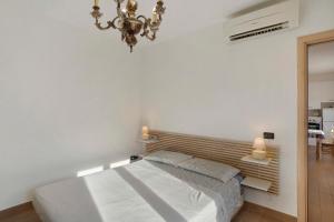 a white bedroom with a bed and a chandelier at Santa Lucia in Imperia