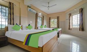 two beds in a large room with windows at Treebo Trend Green Land Kushalnagar in Kushālnagar