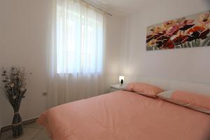 a white bedroom with a bed and a window at Apartment Rinkovec in Klimno