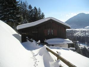 domek pokryty śniegiem na szczycie góry w obiekcie Bojernhof w mieście Ruhpolding