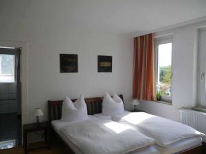 ein Schlafzimmer mit einem großen weißen Bett mit weißen Kissen in der Unterkunft Böhler's Landgasthaus in Bad Driburg