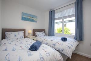 two beds in a bedroom with blue towels on them at Spacious 3 Bedroom Lodge with Rural and Sea Views in Soar