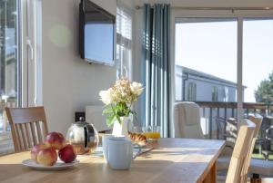 a table with apples and a vase of flowers on it at Spacious 3 Bedroom Lodge with Rural and Sea Views in Soar