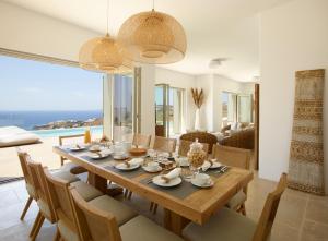 a dining room and living room with a table and chairs at Absolute Paradise Villa Tourlos in Mikonos