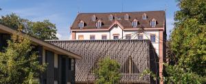 a large house with a roof on top of a building at ODELYA - Stadthotel im Park in Basel