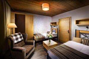 a hotel room with a bedroom with a bed and a chair at Chalet Jasná Wellness Apartment Saskia jacuzzi & sauna in Demanovska Dolina