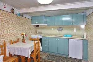 een keuken met blauwe kasten en een tafel met een tafelkleed bij Skopelos house in Castle in Panormos Skopelos