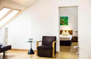 a living room with a chair and a bed at ODELYA - Stadthotel im Park in Basel