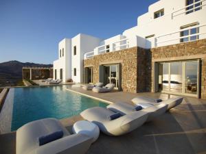 a villa with a swimming pool with lounge chairs at Absolute Paradise Villa Tourlos in Mikonos