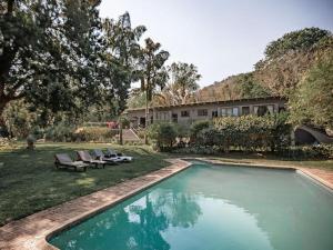 a swimming pool with two chairs and a house at Linvale Country Lodge in Hazyview