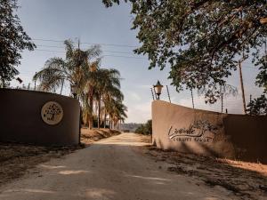 an empty road with a fence and palm trees at Linvale Country Lodge in Hazyview