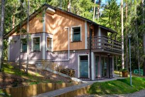 a house in the woods with a balcony at LVM tūrisma un atpūtas centrs "Spāre" in Spāre