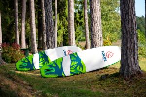 two surfboards laying on the grass next to trees at LVM tūrisma un atpūtas centrs "Spāre" in Spāre