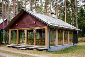a small house with glass windows in a forest at LVM tūrisma un atpūtas centrs "Spāre" in Spāre