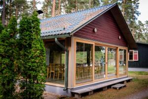 a screened in porch of a red house with glass at LVM tūrisma un atpūtas centrs "Spāre" in Spāre