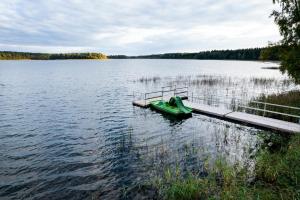 a green boat parked at a dock on a lake at LVM tūrisma un atpūtas centrs "Spāre" in Spāre