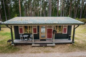 a small green house with a table and chairs at LVM tūrisma un atpūtas centrs "Spāre" in Spāre