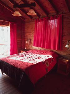 a bedroom with a bed with red curtains at Cabaña Ilusión - Complejo Marea in Tigre