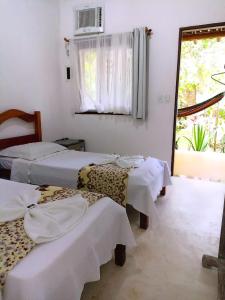 a group of beds in a room with a window at Pousada Grafite in Trancoso +84 photos