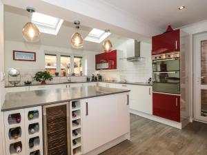 uma cozinha com balcões brancos e armários vermelhos em Sandy Toes em Christchurch